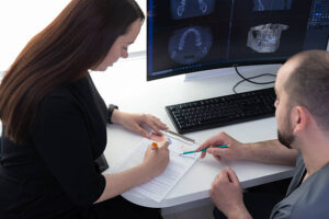 Patient reviewing detailed dental treatment cost estimate with office staff at Aspen Dental clinic